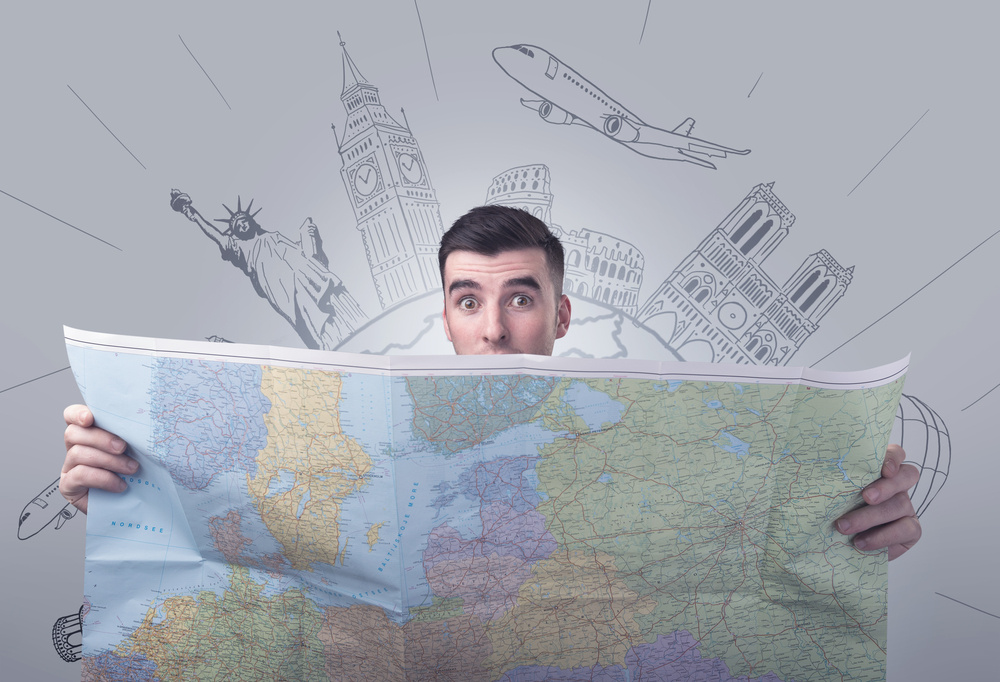 Handsome young man holding a map with famous sightseeing destinations above his head