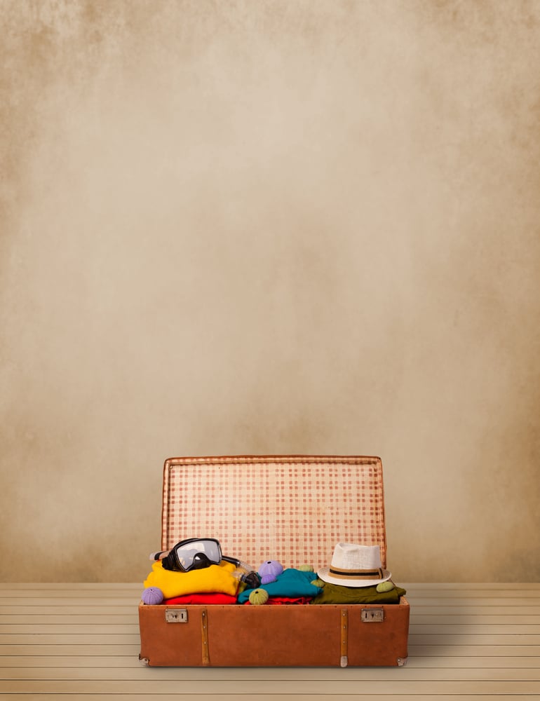 Retro tourist luggage with colorful clothes and copyspace on grungy background